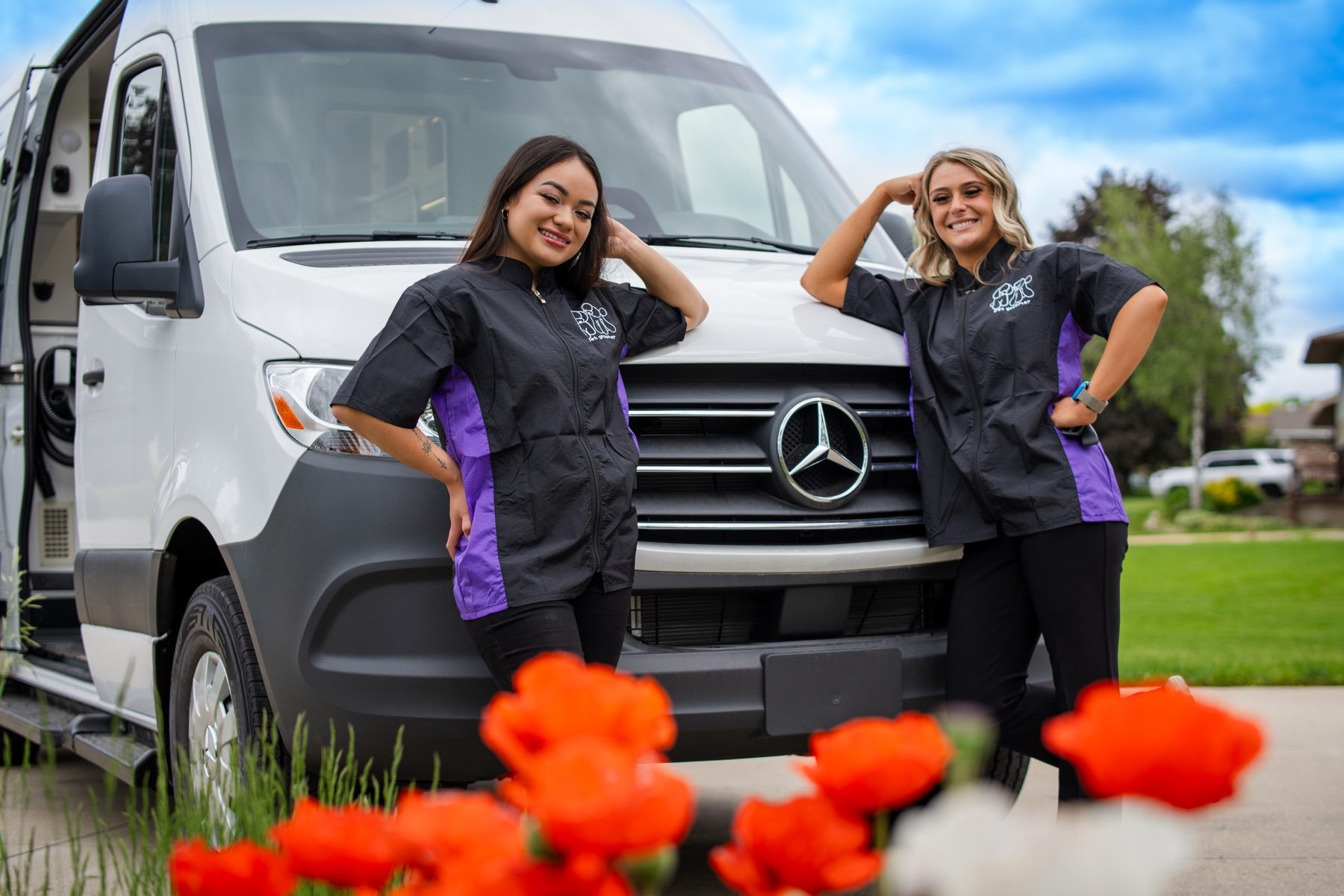 Two Wag'n Tails groomers smiling beside their mobile grooming van