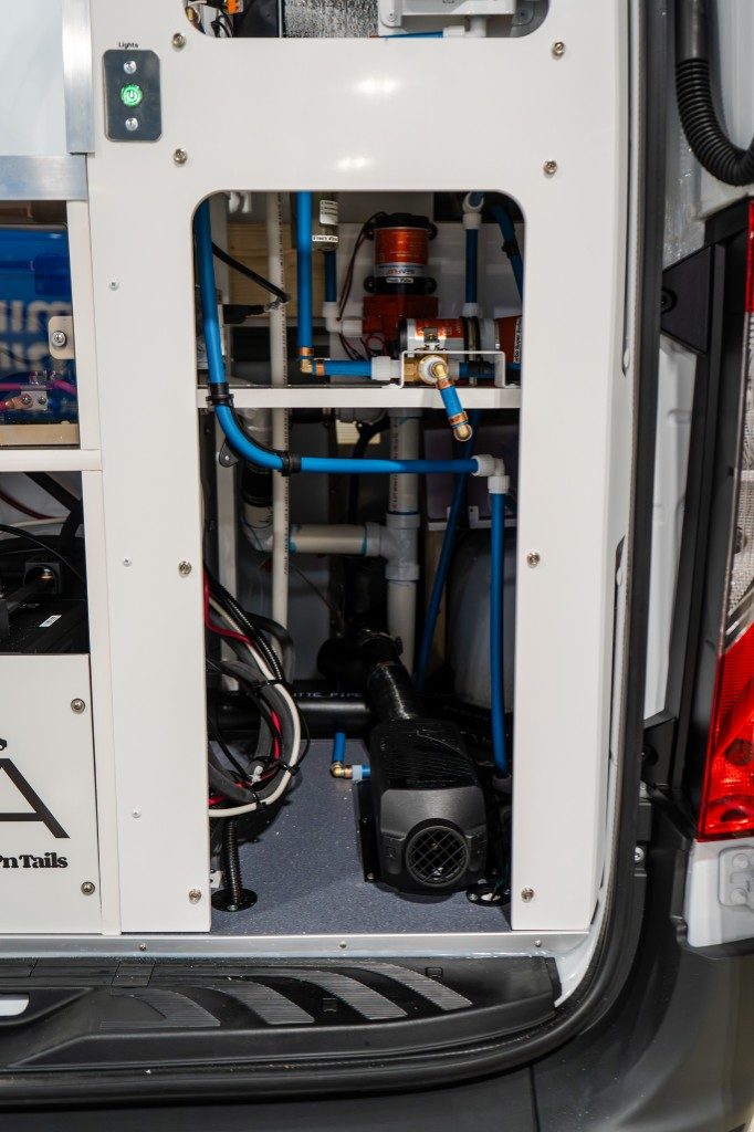 Rear utility compartment showing the fuel-fed furnace, water lines, and organized mechanical layout