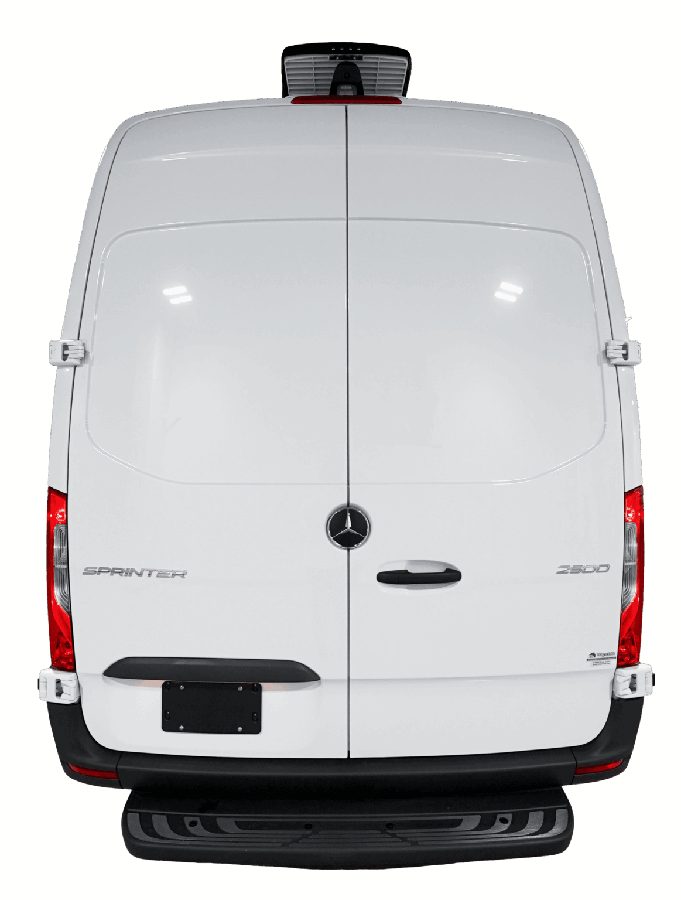Groomer holding a small dog beside an open Quantum van