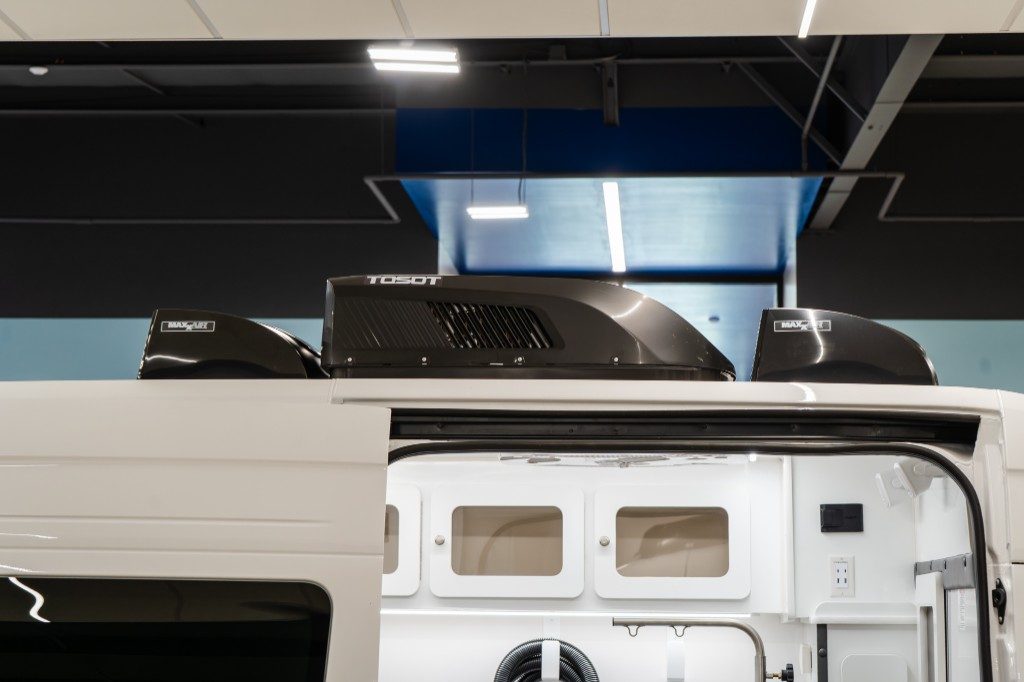 Low-profile black Dometic rooftop air conditioner and MaxxAir vents on a white Quantum Sprinter
