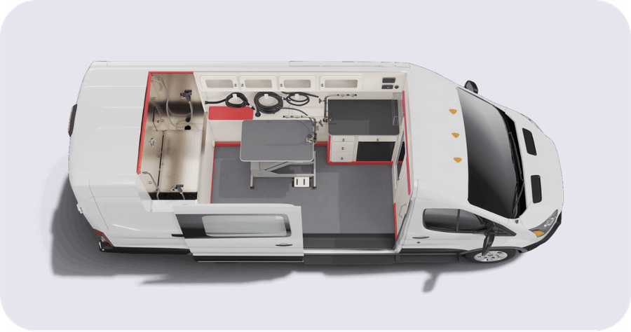 Top-down view of a white ambulance van interior with red-accent cabinets, a worktable, and medical equipment.