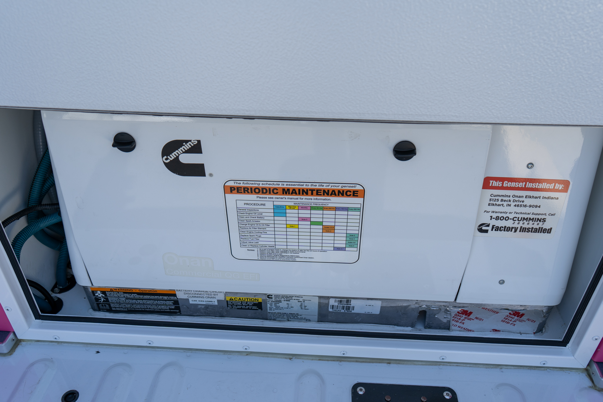 Close-up of a Cummins generator exterior panel featuring a periodic maintenance sticker and maintenance schedule grid.