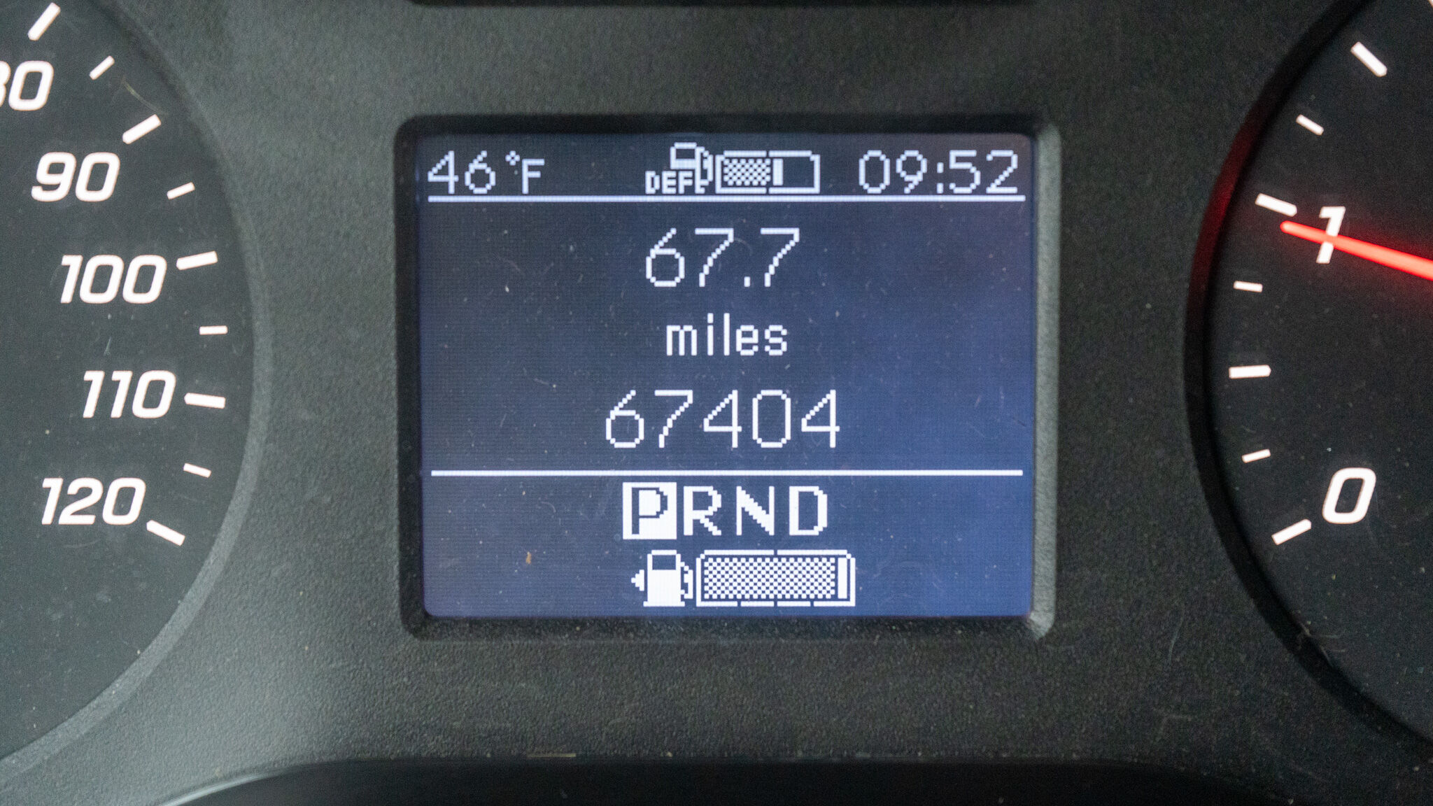 Digital car dashboard: outside temp 46°F, time 09:52, trip 67.7 miles, odometer 67,404 miles, gear indicator showing P R N D.