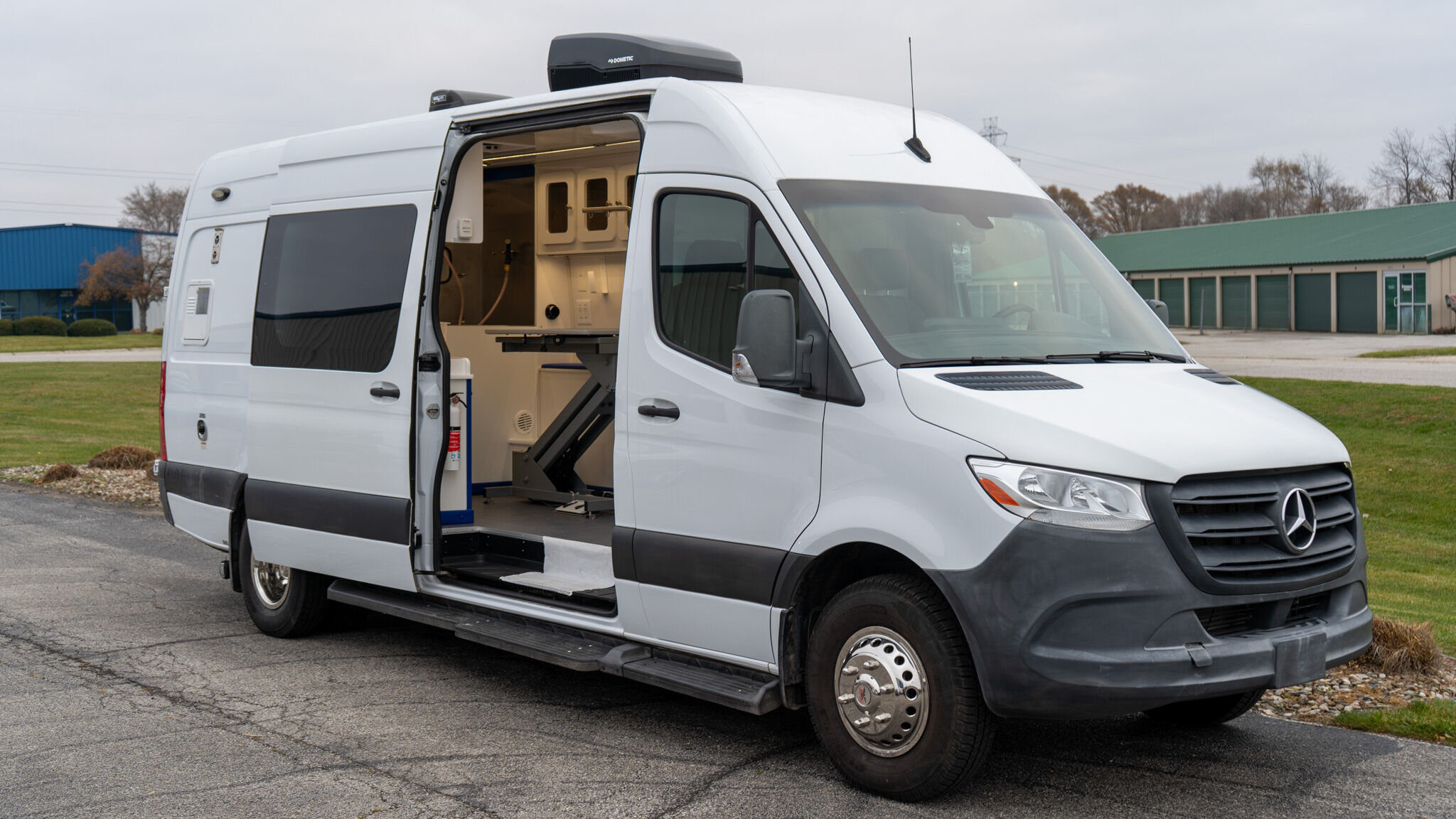 White utility van with the side door open, revealing a workshop interior and equipment inside.
