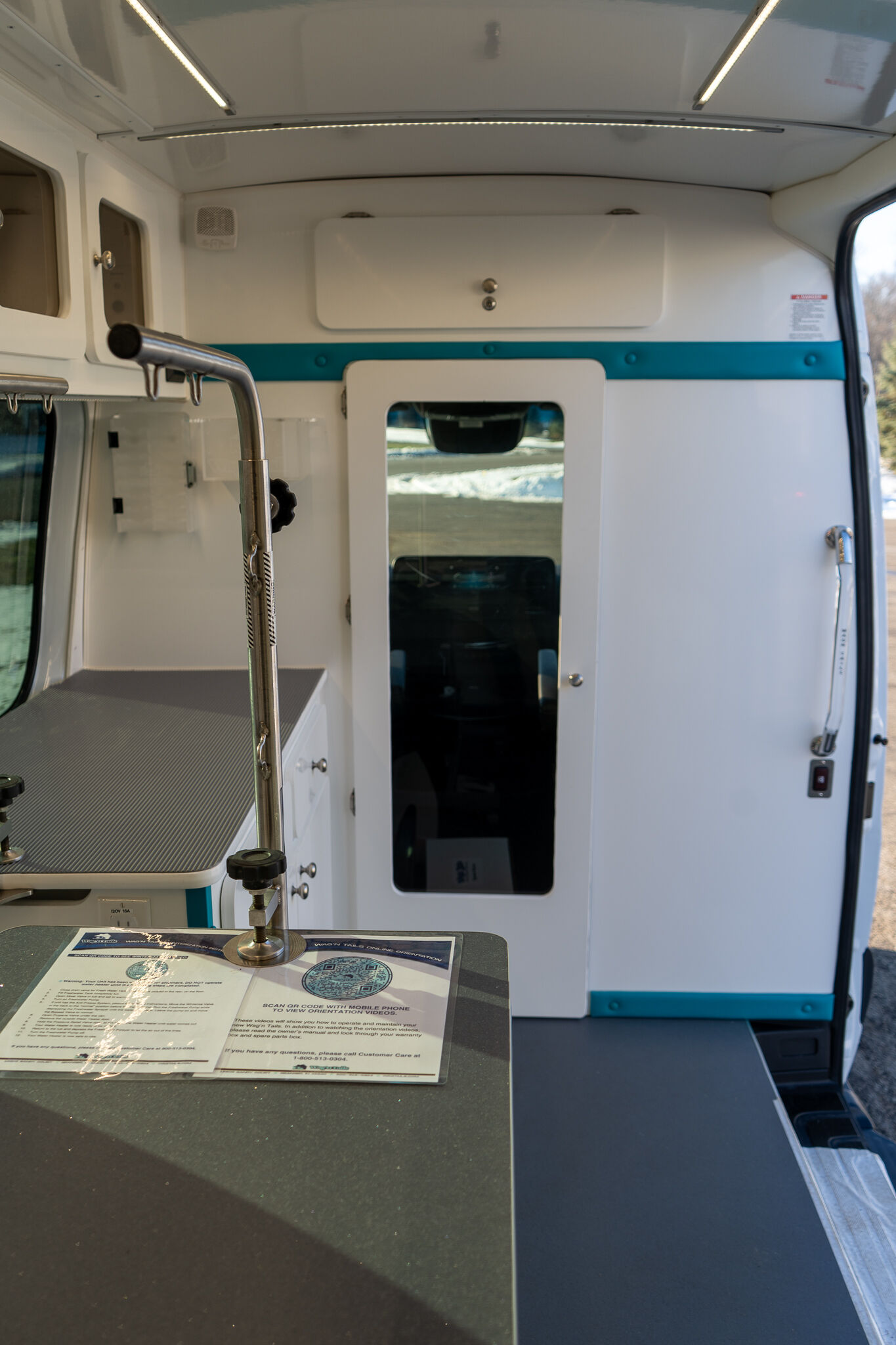 Interior of an ambulance with white cabinets, a teal stripe, and a countertop in the foreground.