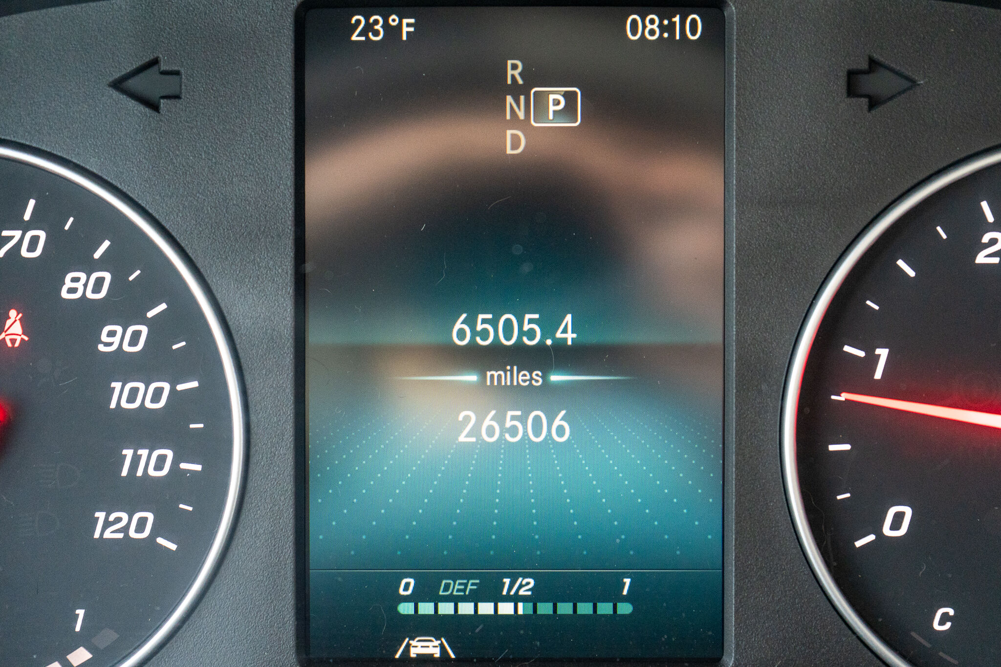 Center instrument cluster: gear in Park, odometer reading about 26,506 miles, trip 6,505.4 miles, outside temperature 23°F, time 08:10, with left and right speedometer/rpm dials partially visible.