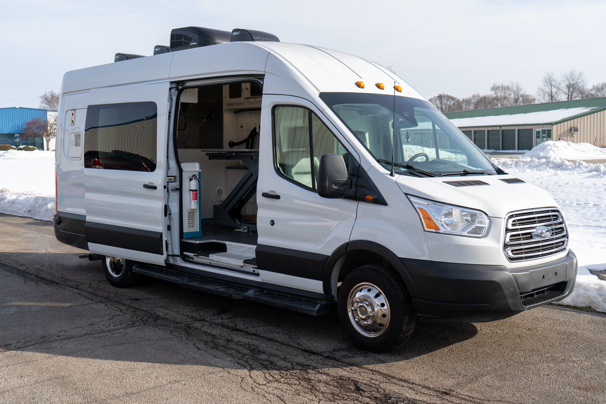 White cargo van with side door open, interior equipment and storage visible in a snowy outdoor lot.