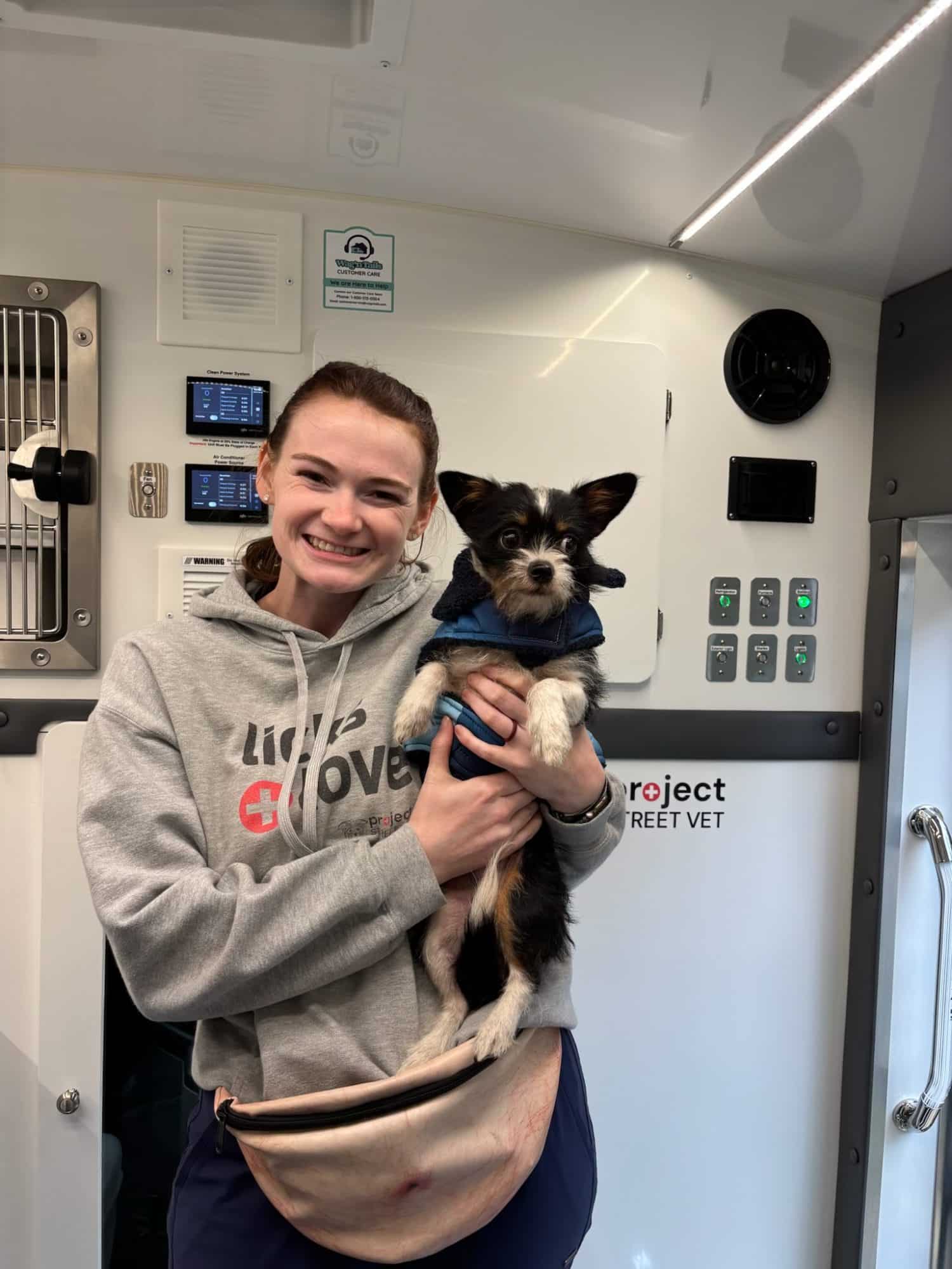 Wag'n Tails team member holding a small dog inside the Project Street Vet mobile veterinary unit